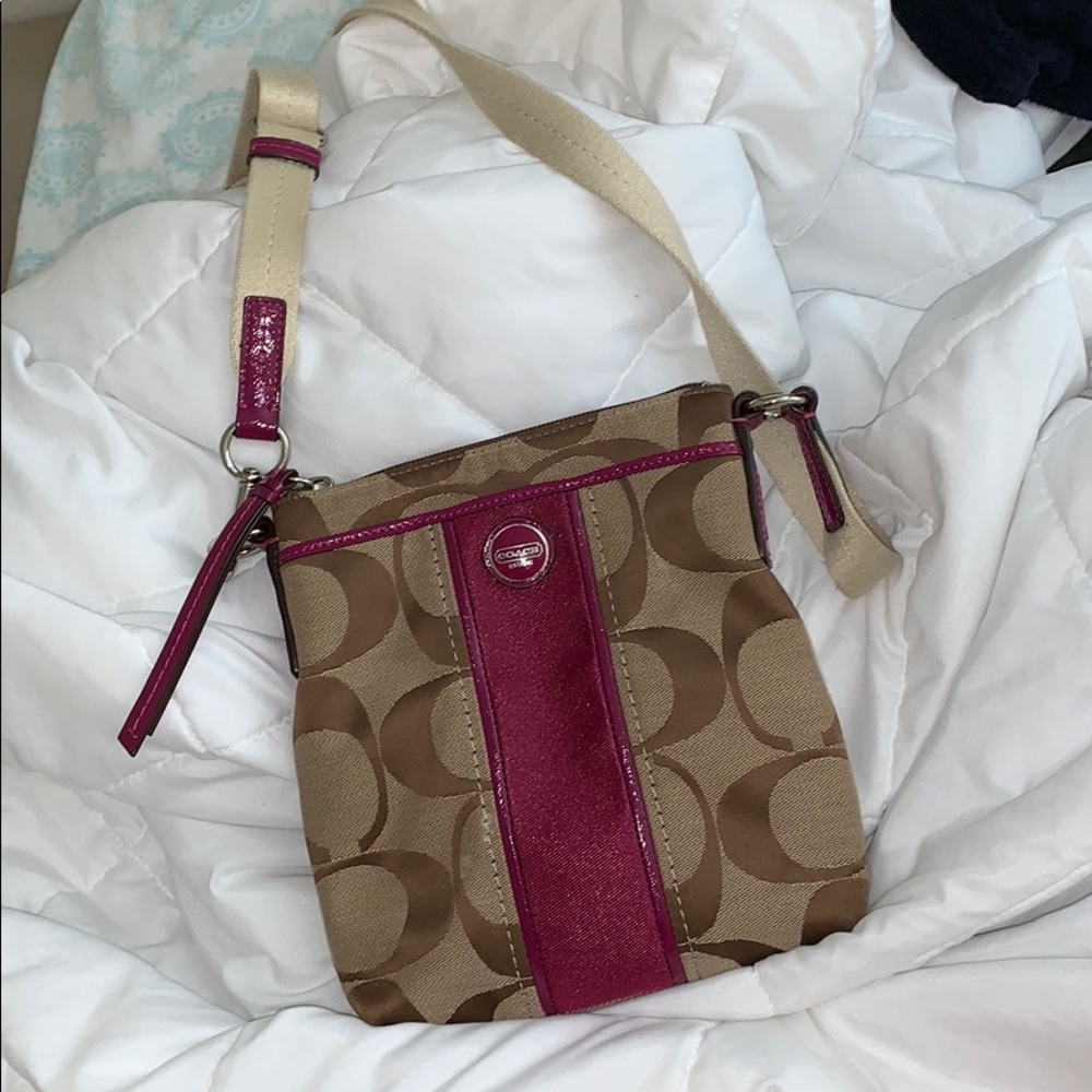 A coach cross body purse with purple detailing